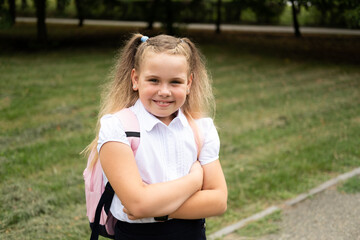 happy blonde curly schoolgirl in school uniform with pink backpack back to school outdoor