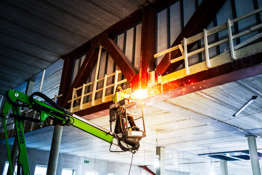 Construction worker welding from crane