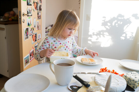 Girl buttering toast at table