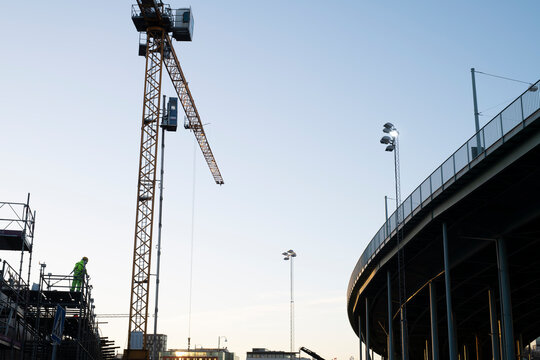 Construction worker standing on scaffolding by crane