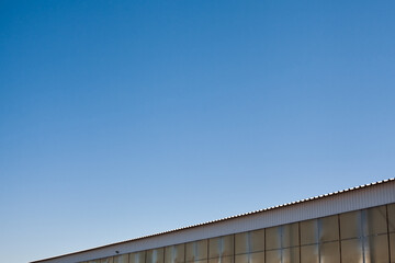 The upper part of an industrial building against the backdrop of a blue clear sky during the day. Background image for your design or illustrations.