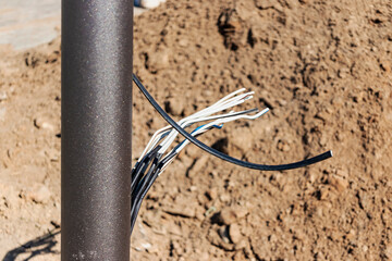 Lamppost with open hole. Inside is a power switch and electrical cables. Electrical connection for a lamppost. Installation of street lighting.