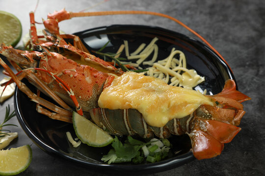 Close up of Painted Spiny Lobster baked with cheese on black table background. Seafood concept.