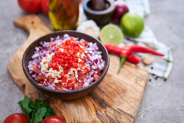 making salsa dip sauce - chopped garlic, tomatoes and onion in wooden bowl