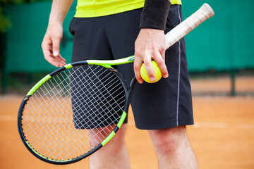 Closeup male tennis player holding racket and ball. - Powered by Adobe