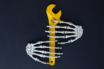 Skeleton palms and a yellow adjustable wrench on a black background