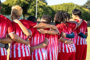 Obraz premium Rear view of multiracial male players in red uniforms with arms around standing side by side
