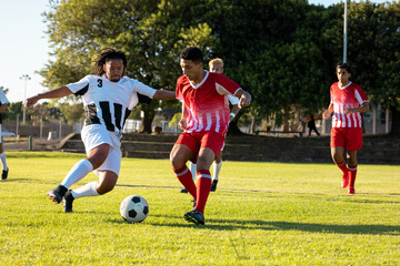 Multiracial male players running and chasing the ball during soccer match at playground