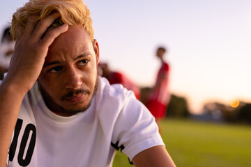Caucasian stressed male soccer player with head in hand sitting against clear sky at playground © WavebreakMediaMicro