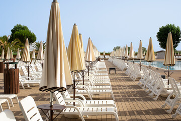 Sunbeds and umbrellas by the hotel pool, season opening, right side