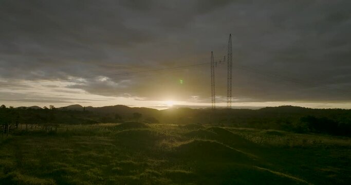Aerial flying towards dramatic sunset, overhead power line in foreground