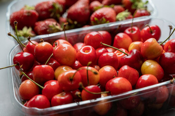 Ripe strawberries and sweet cherries. A new crop of red berries in a clear tray in the background. Healthy Food. Selective focus.