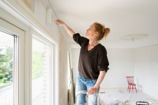 Woman painting wall in house