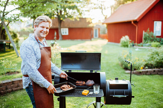 Young man cooking meat on barbecue
