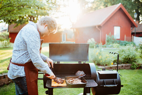 Young man cooking meat on barbecue