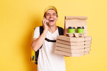 Indoor shot of happy laughing man courier with thermo backpack in white T-shirt and cap isolated...