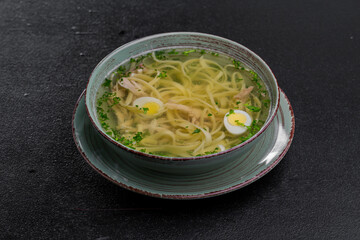 Soup with boiled eggs, noodles, chicken meat, parsley