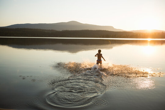 Boy splashing in Ottsjo Lake at sunset in Valadalen Nature Reserve Sweden