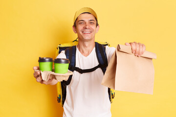 Portrait of kind optimistic deliveryman with thermo backpack in white T-shirt and cap giving order...