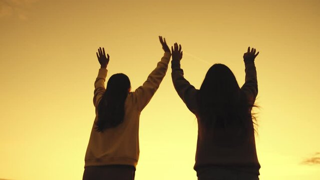 happy girls jump with raised hands sunset. success joy achieving teamwork. silhouette winners competition. girls with long hair against sky. beach party dancing evening. concept friendly team success