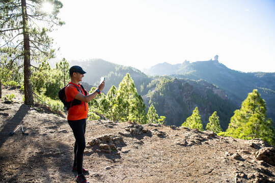Man photographing with smart phone on mountain