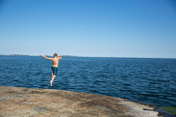 Boy diving from rock in to sea