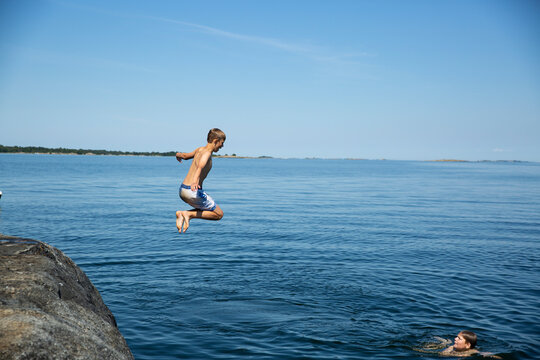 Boy diving from rock in to sea