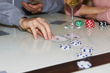 Laying out cards on the table in poker game. Players with dices and cards. Glass of champagne. Gambling concept. Candid moment. Poker background photography. Selective focus