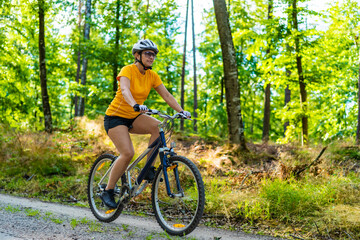 Woman riding bike in forest
 - Powered by Adobe