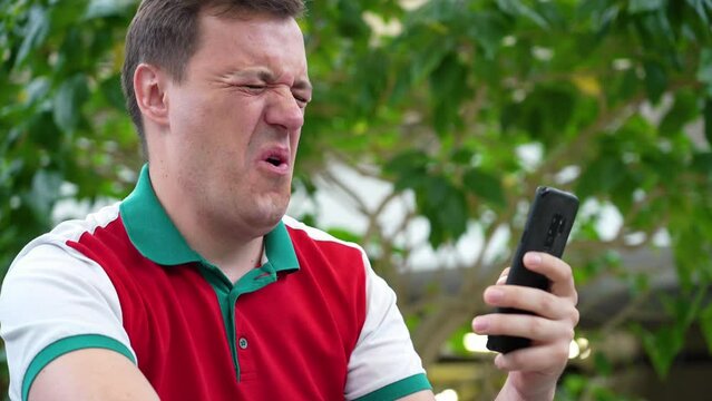 Confused cringe businessman is unpleasantly shocked by what he saw on screen mobile phone, crisis, pay debt. Disgusted and overwhelmed millennial man stares at screen of smart phone.