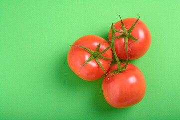 top view of tomatoes on a branch on a green background with copy space