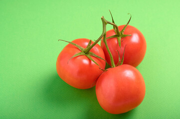 tomatoes on a branch on a green background with copy space