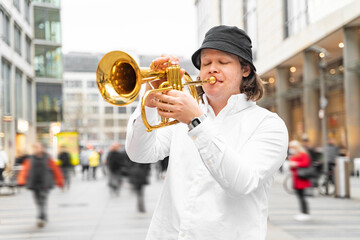 Young caucasian blond man with long hair and closed eyes in white shirt and hat playing jazz on...