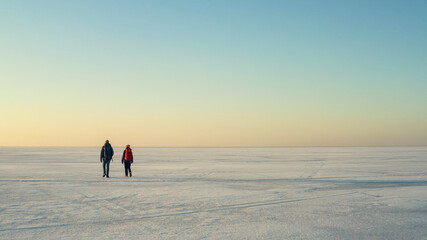 The two people with backpacks walking through the huge snow field