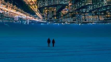 The two people walking through the night snow field on the citylights background