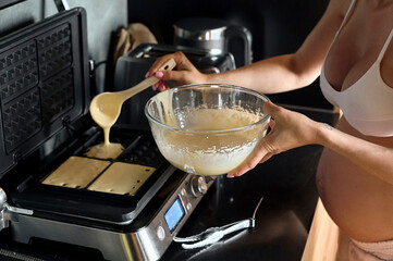 Beautiful pregnant woman making fruits smoothies with blender. H