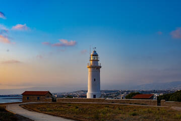 Fototapeta na wymiar Beautiful sunset on coastline of Kato Paphos. The lighthouse in ancient complex park Kato Paphos.