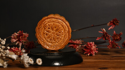 Traditional moon cakes decorating with dried flowers on wooden table. Chinese Mid autumn festival...