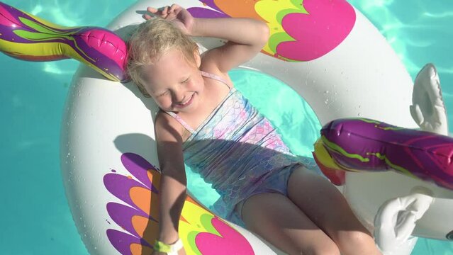 Happy child girl swims and sunbathes in the pool on an inflatable ring