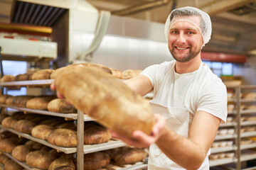 Junger Bäcker zeigt ein frisches und gesundes Biobrot