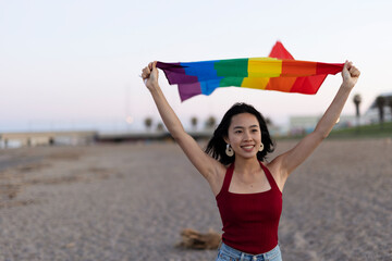 Young girl with a pride flag at the beach. LGBT community.