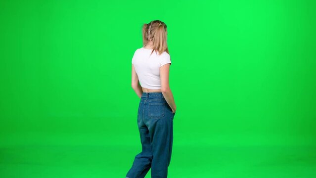 Young woman walking down the street on a green background, a passerby on a walk, chroma key template, female in a white t-shirt and blue jeans.