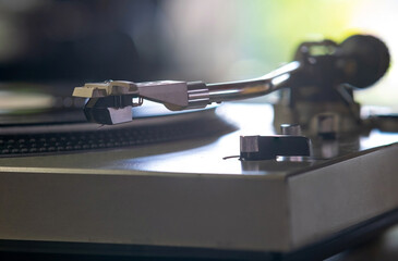 Focus on The Headshell Cartridge and Stylus of Classic Vintage Vinyl Record Player or Turntable Playing on Vinyl Record Music
