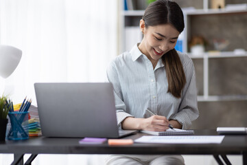 Business of Asian woman or accountant working on calculator to calculate business data, accounting document, and laptop computer at home office, business finances and calculate concept