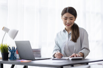 Business of Asian woman or accountant working on calculator to calculate business data, accounting document, and laptop computer at home office, business finances and calculate concept