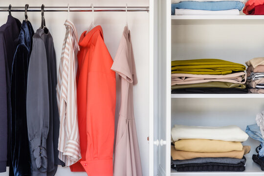 Shelves with colorful clothes in a white wardrobe close-up, minimalism style