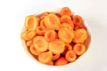 Pitted Apricots with Pits on a White Dish
