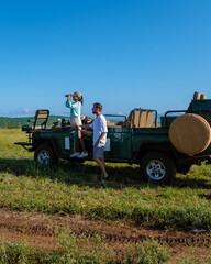 couple men and Asian woman on safari in South Africa, South Africa Kwazulu Natal, luxury safari car during a game drive, couple men and woman on safari in South Africa.  © Fokke Baarssen