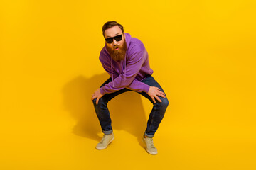 Full length photo of positive funny guy dressed purple sweater dark eyewear dancing isolated yellow color background