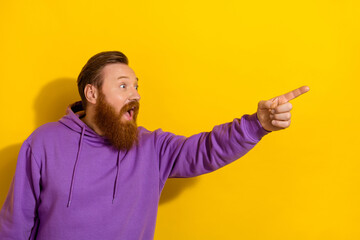 Photo of funny impressed guy dressed purple sweater looking pointing finger empty space isolated yellow color background